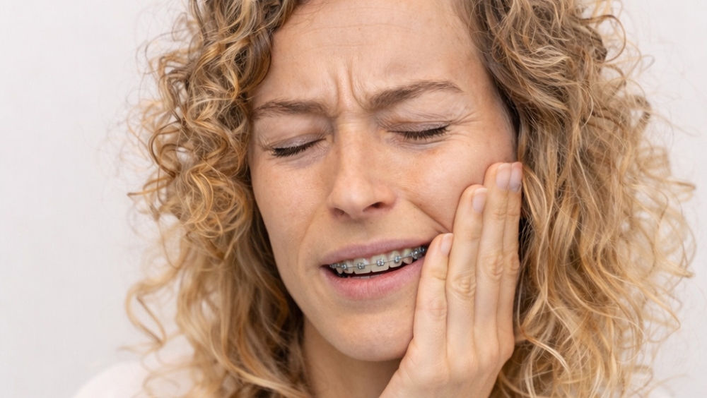 Una paciente con ortodoncia sufriendo dolor provocado por los brackets.